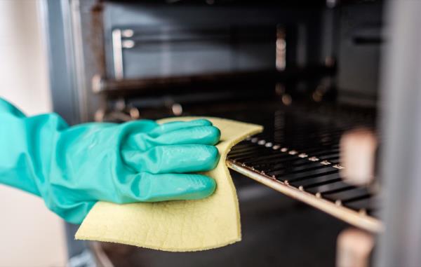 gloved hand cleaning oven